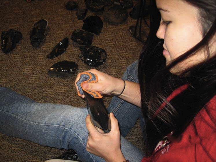 Anthropology student Sarah Mooso carefully polishes obsidian cobbles for the exhibit.