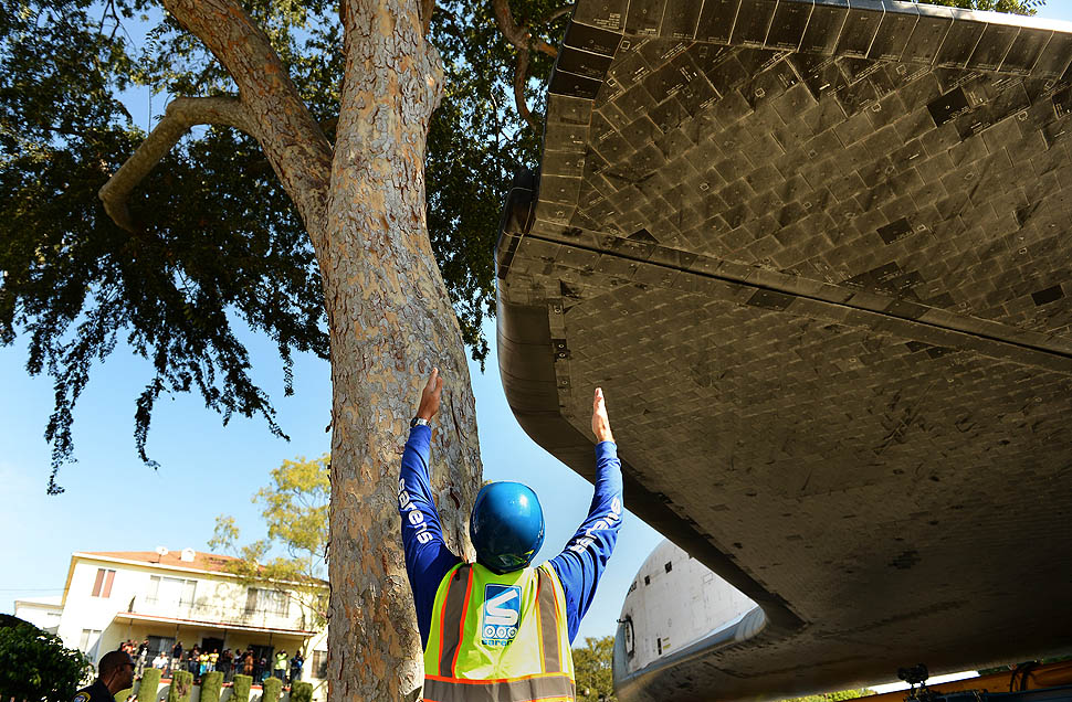 A crew member carefully guide the shuttle Endeavour past a tree along Crenshaw Drive in Inglewood, CA.